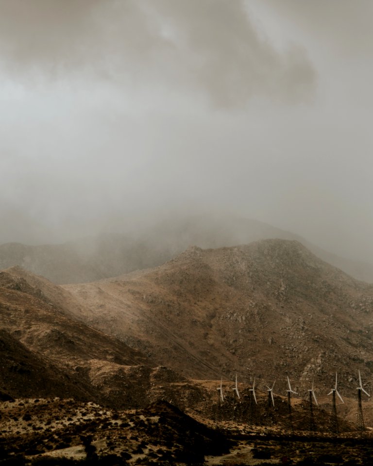 white wind turbines beside mountain