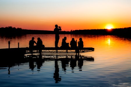 group of people on wooden dock during sunset in silhouette photography photo