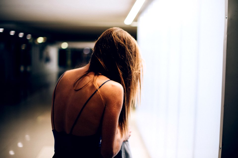 woman in black spaghetti strap top standing by the window