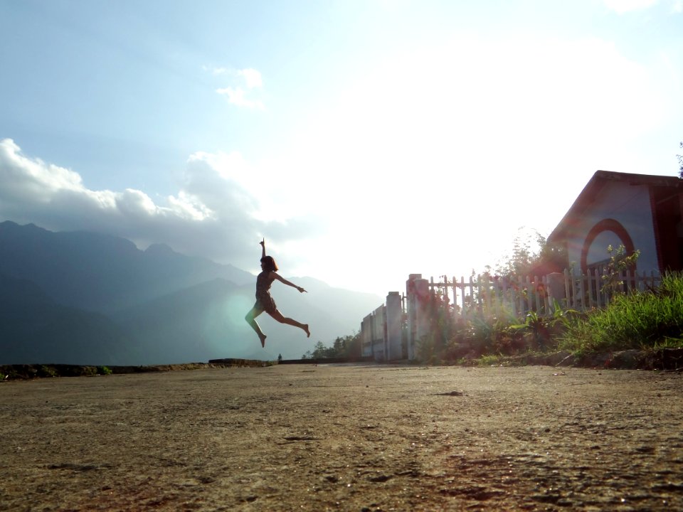 woman jumping at daytime near house