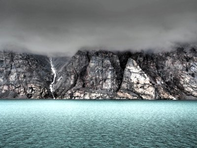 gray cliff beside body of water covered by fog photo