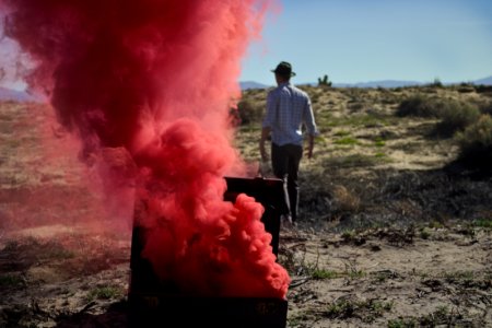 red smoke bomb on chest near man wearing black cap