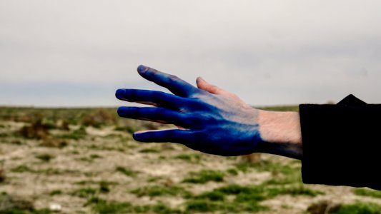 A person reaching out with their blue paint covered hand.