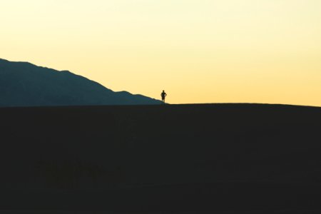 silhouette of person standing on mountain photo