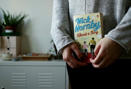 person holding Nick Hornby's About a Boy book