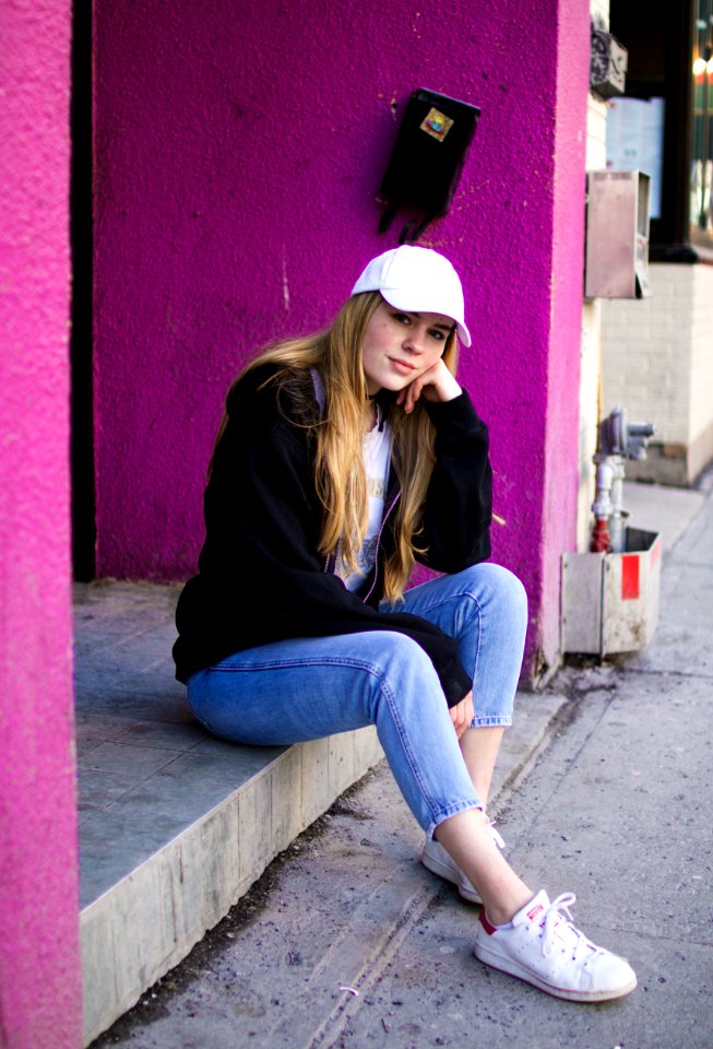 woman in black jacket and blue jeans sitting outdoors