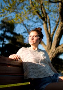 selective focus photography of girl sitting on bench during daytime photo