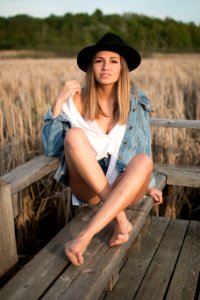 woman sits on wooden bench near field photo