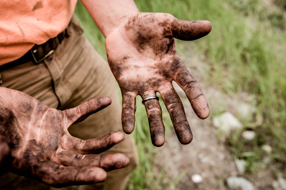 A man with his hands covered with mud