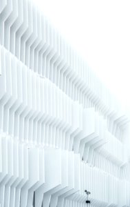 A security camera near parallel white ribs in a building facade in Madrid
