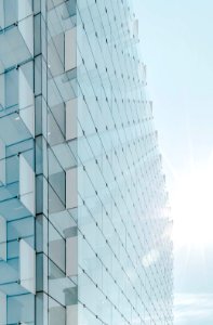 glass panel high-rise building under blue sky with sun raise photo