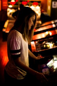 woman in white and black shirt standing in front of arcade machine photo