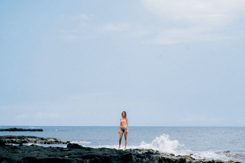 woman standing on rock formation near body of water photo