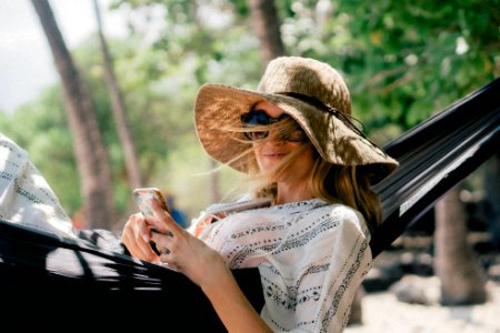 woman lying on black hammock while holding phone photo