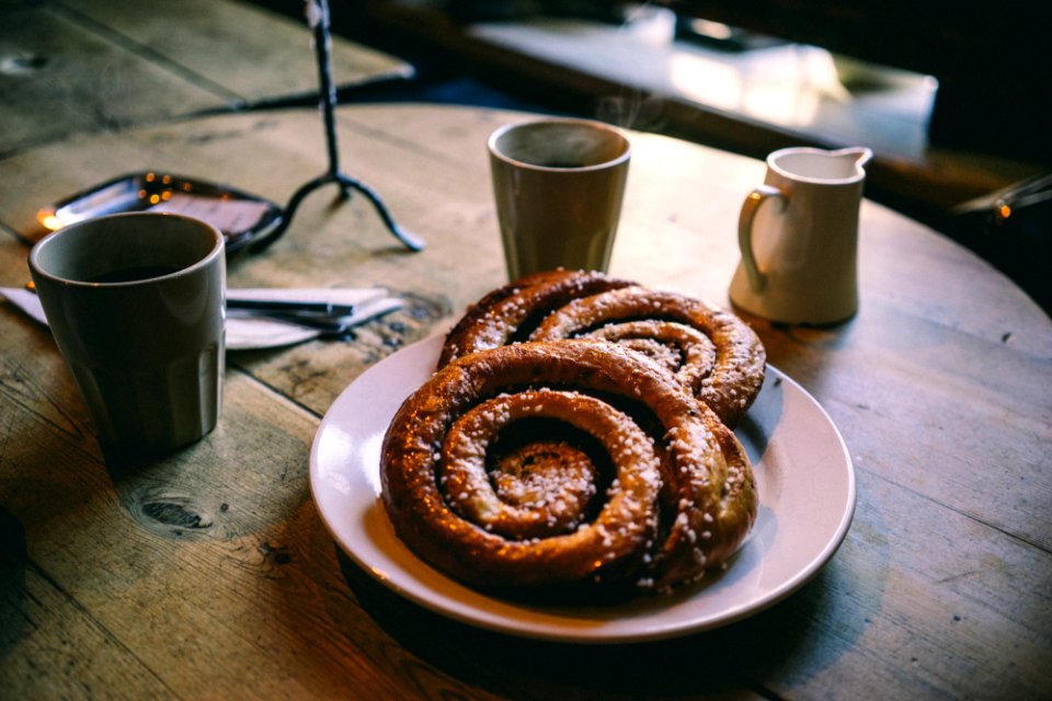 plate of glazed bread near mugs on tabletop