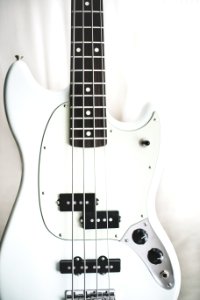 white and black electric bass guitar on white surface photo