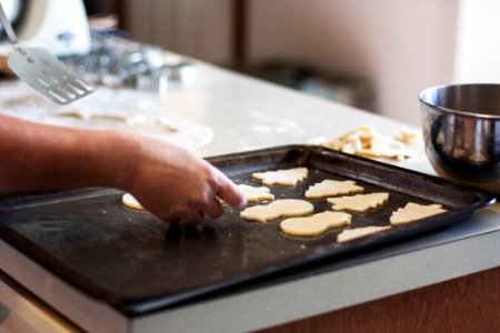 person lining assorted-shaped cookies on baking sheet inside kitchen photo