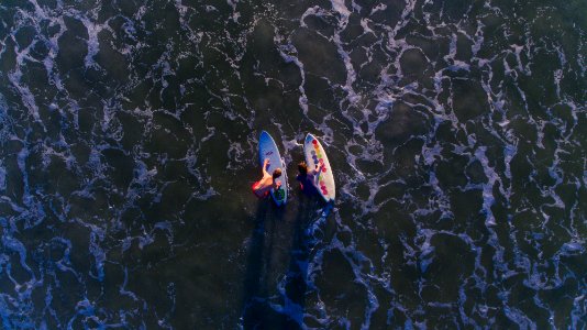 top view photo of two person with surfboards on water photo