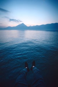 man sitting beside calm body of water