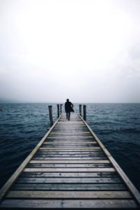 man walking on dock surrounded by ocean during daytime photo