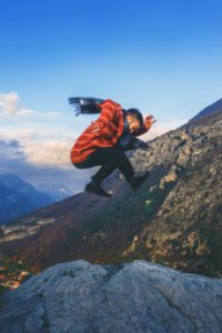 man doing stunt on cliff during daytime photo