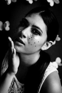 Black and white shot of attractive woman with dark hair and face glitter