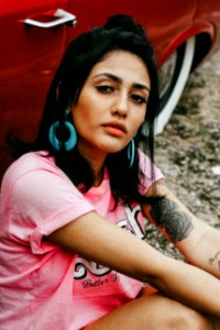 woman sitting beside red car