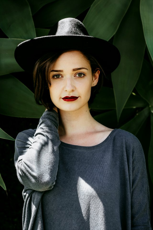 woman standing near trees wearing black hat photo