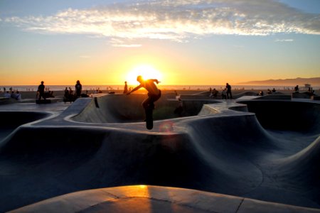 silhouette photo of man riding skateboard on skateboard ramp field photo