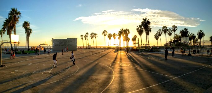 people playing basketball at court during sunset