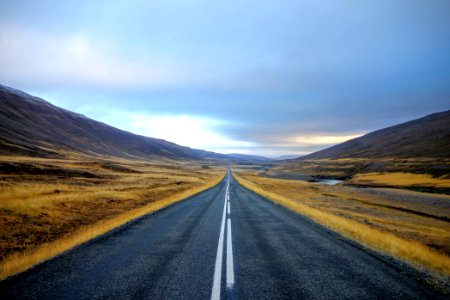 landscape photography of black asphalt road with white line surrounded by brown grass field during daytime photo