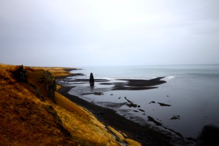 brown mountain near seashore under cloudy sky photo