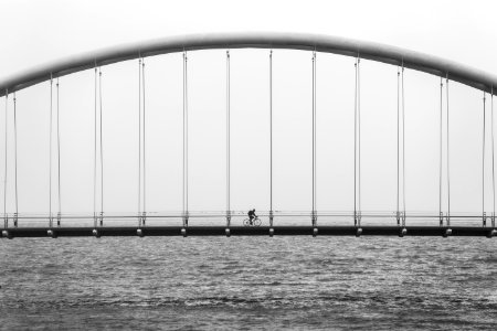 gray scale photo of person driving bike on bridge photo