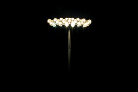 Floodlights shining at the top of a light pole with a pitch black background photo