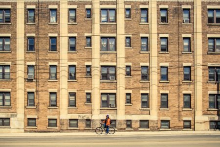 person riding bicycle near brown building photo