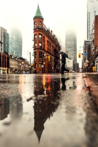 man using umbrella crossing the street during daytime photo