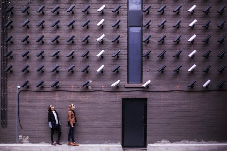 two women facing security camera above mounted on structure
