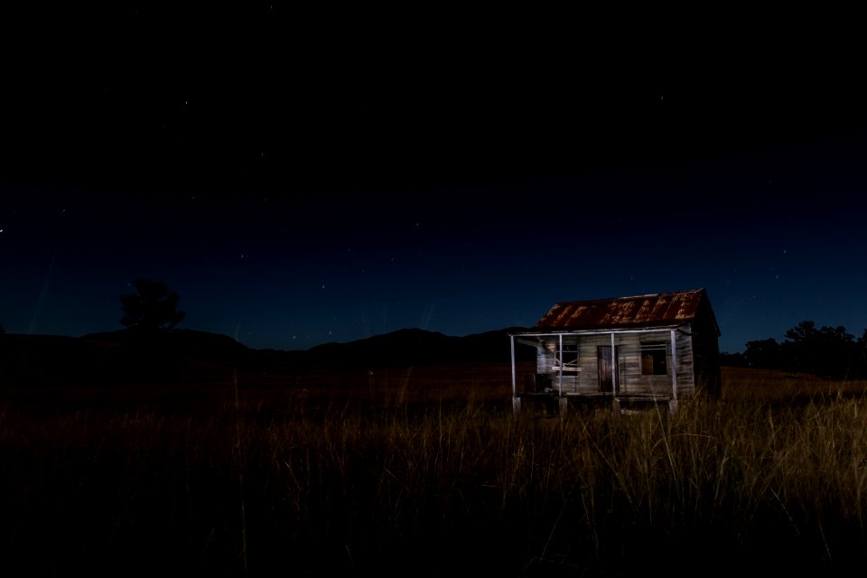 gray and brown wooden house surrounded by grass near mountain
