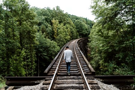 man standing on railway surrounded by trees photo