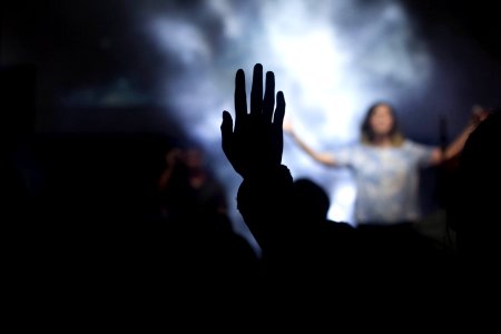 silhouette of person with right hand on air in front of woman on stage photo