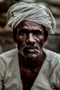 man wearing gray turban smoking cigarette in closeup photography photo