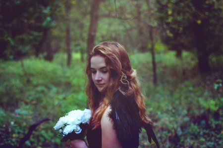 shallow focus photo of woman in black top holding white flowers photo