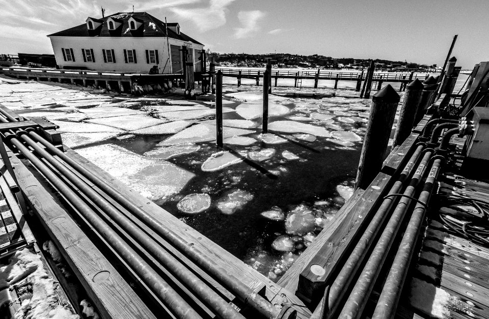 grayscale photo of a wooden fence with snow on the ground