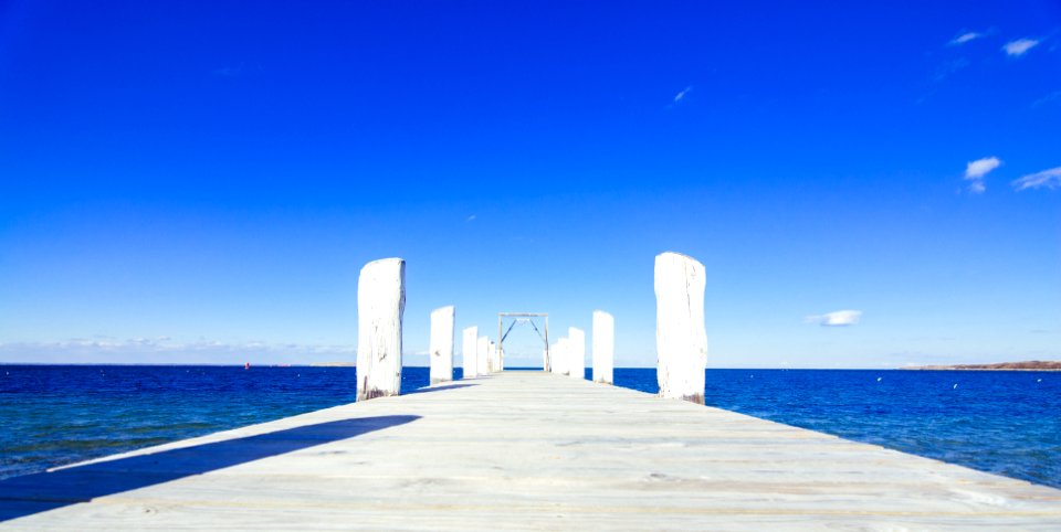 brown wooden dock on blue sea under blue sky during daytime photo