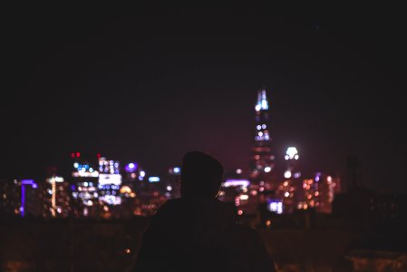 man in black hoodie standing near city buildings during night time