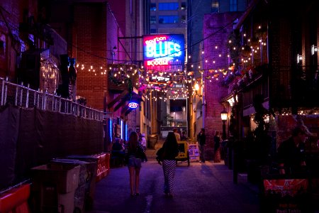 People walking through a downtown street under a line of lights. photo