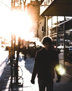 man walking on sidewalk beside glass wall