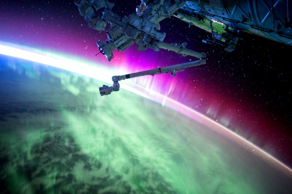 photography of purple and green aurora beam below grey space satellite
