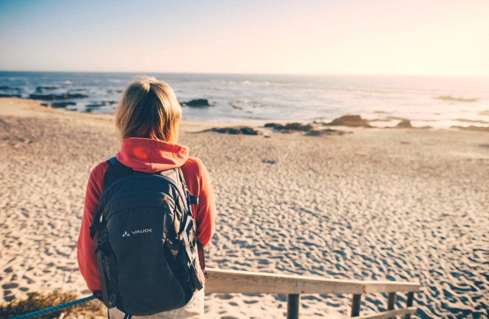 woman in black and red hoodie standing on beach during daytime