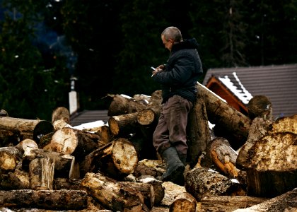 man in black jacket and brown pants sitting on brown log during daytime photo